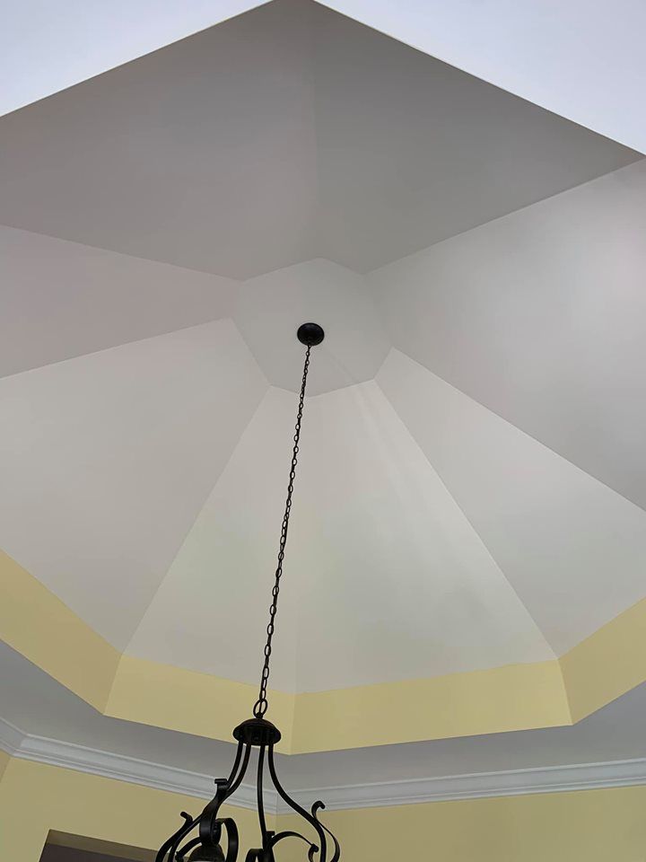 A high-angle view of a white octagonal ceiling with a chandelier hanging from its center.