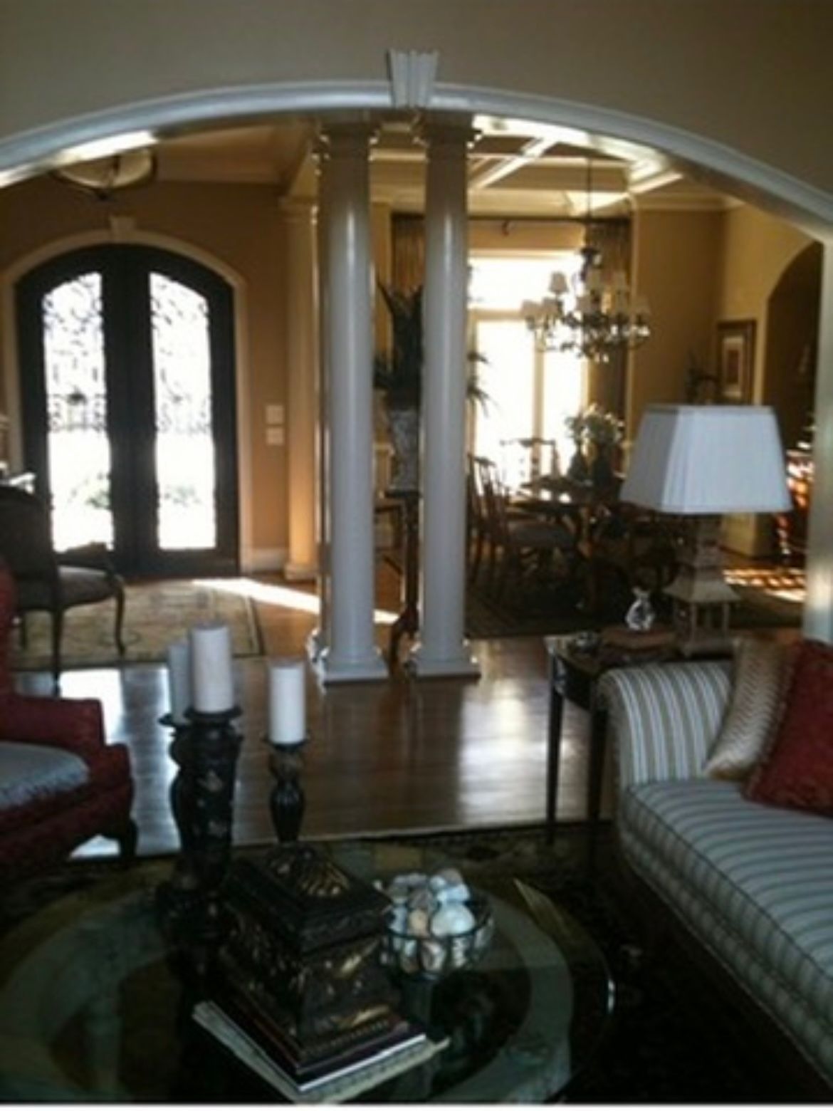 Living room with columns, arched doorway, ornate furnishings, and a view of a dining room.
