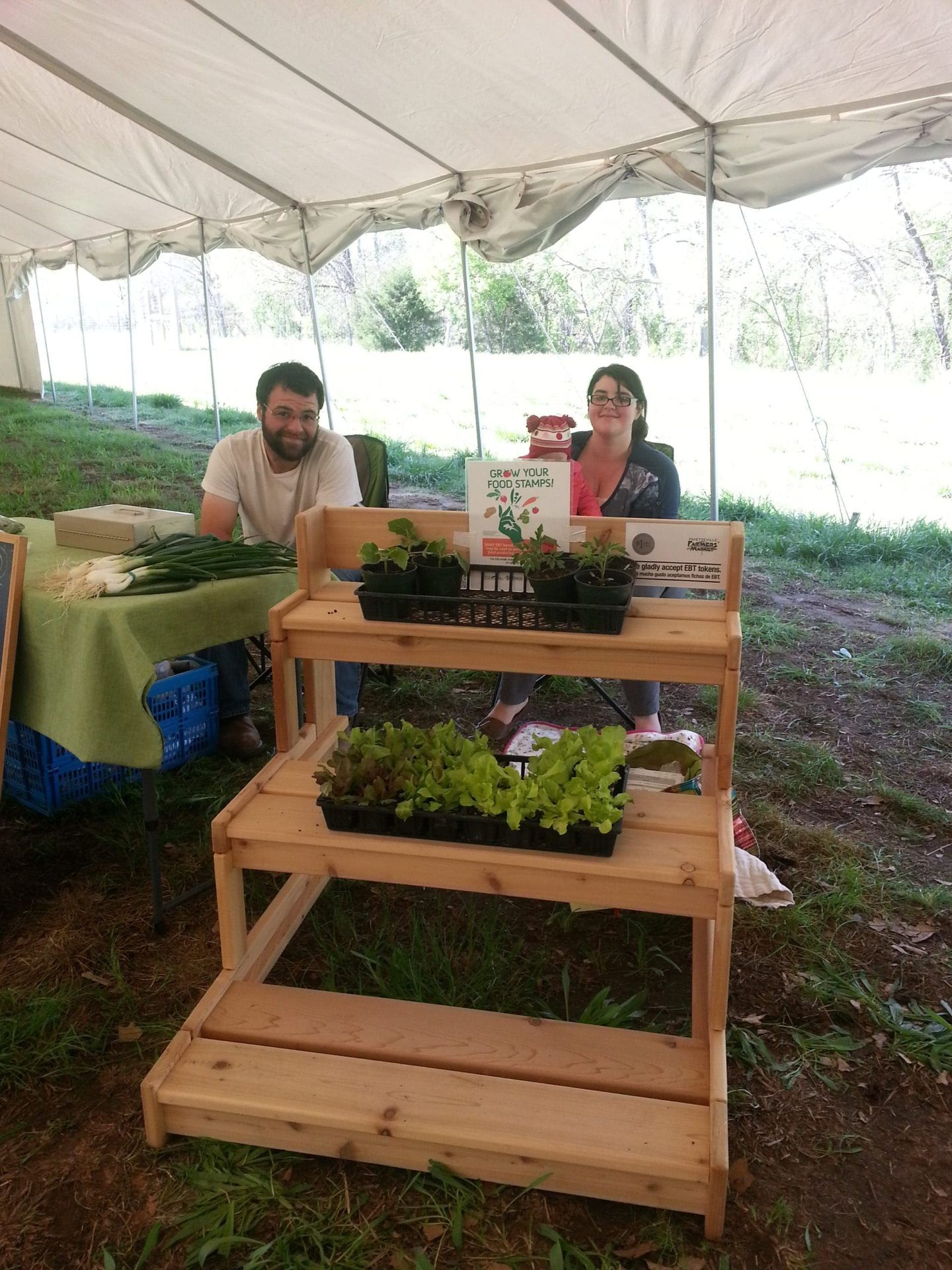 A man and a woman are sitting at a table under a tent.