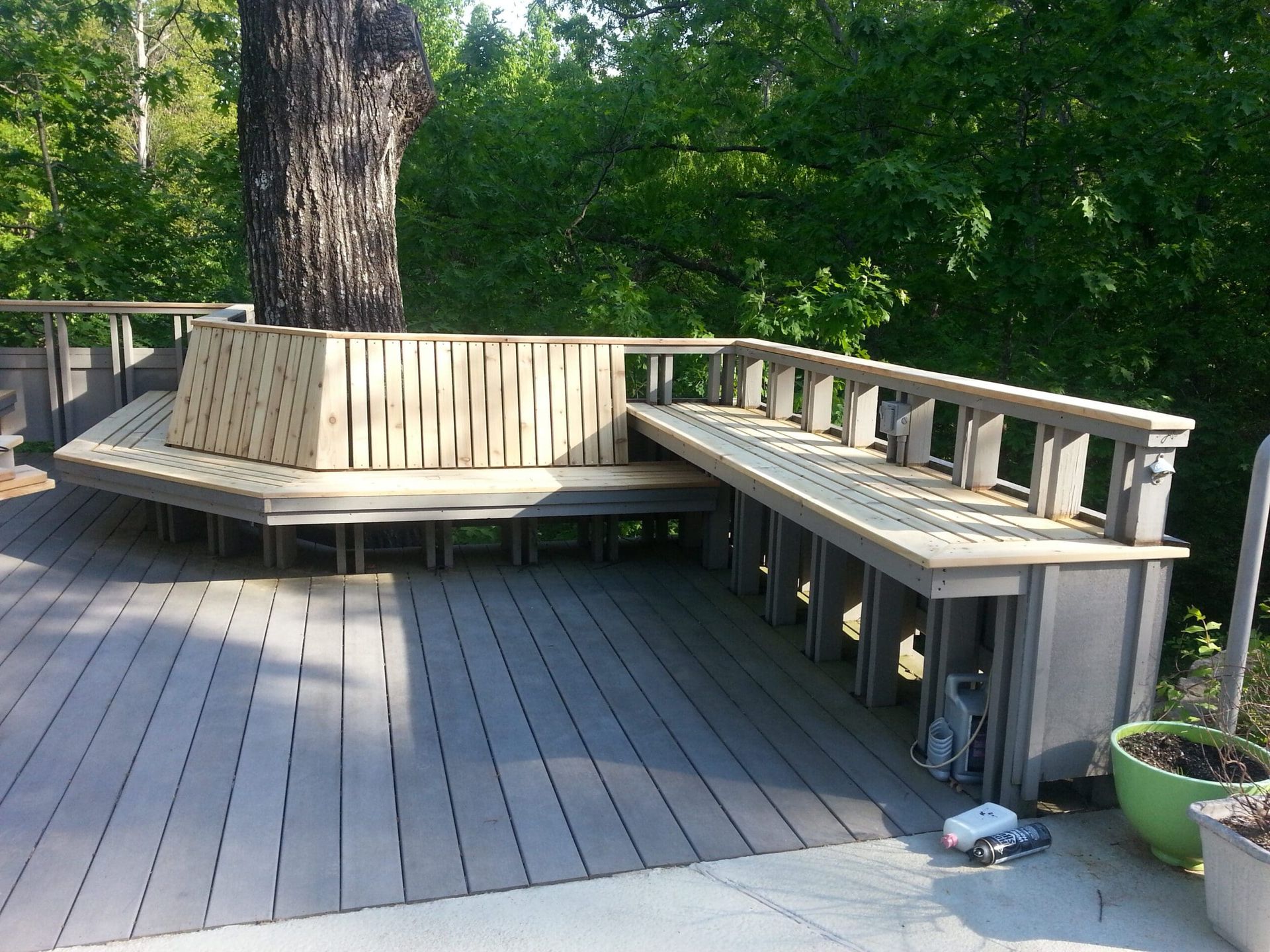 A wooden deck with a bench under a tree