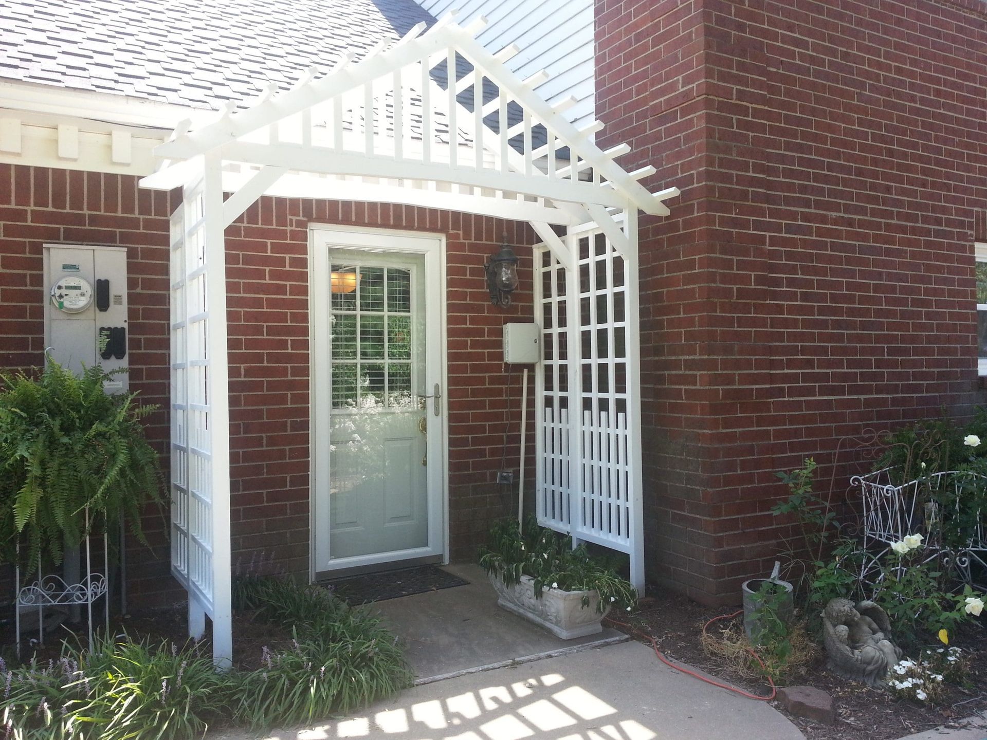 A brick house with a white pergola over the front door