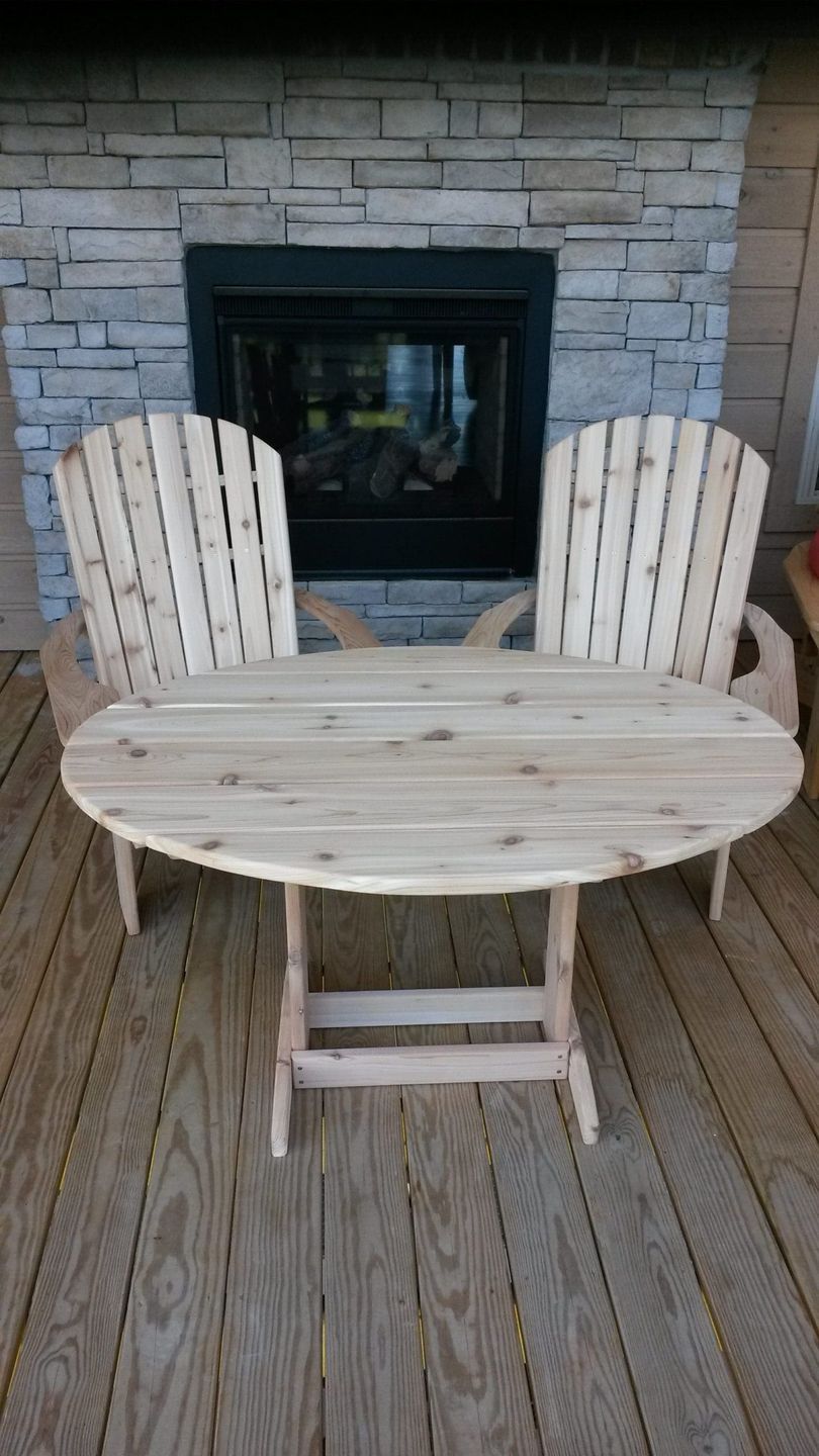 A wooden table and chairs are sitting on a wooden deck in front of a fireplace.
