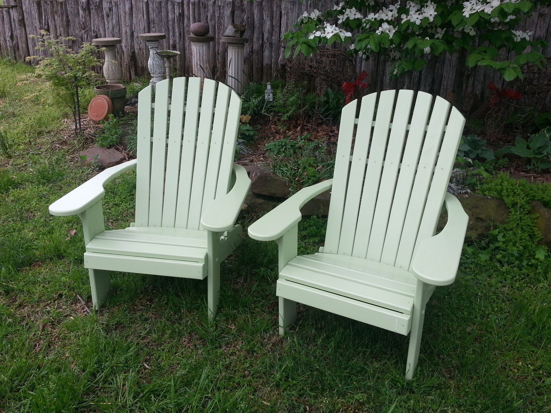 Two green adirondack chairs are sitting in the grass