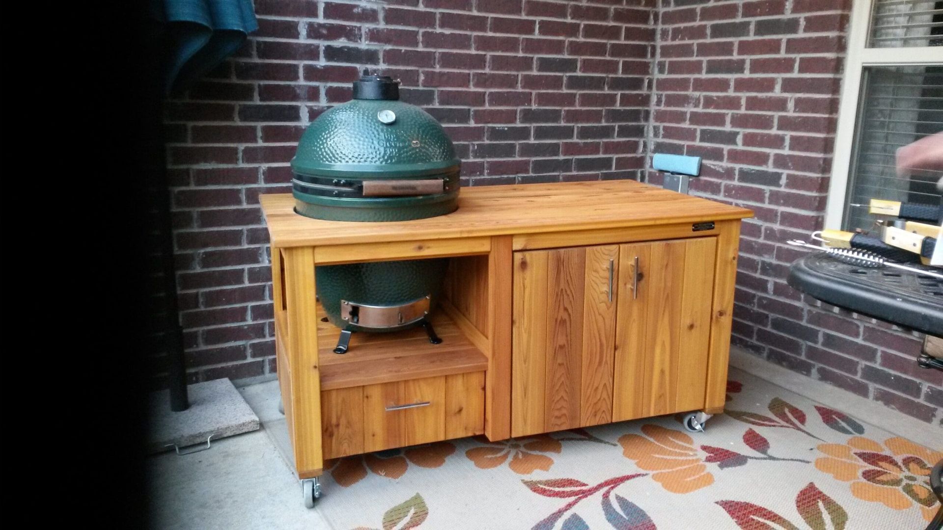 A large green grill is sitting on top of a wooden table.