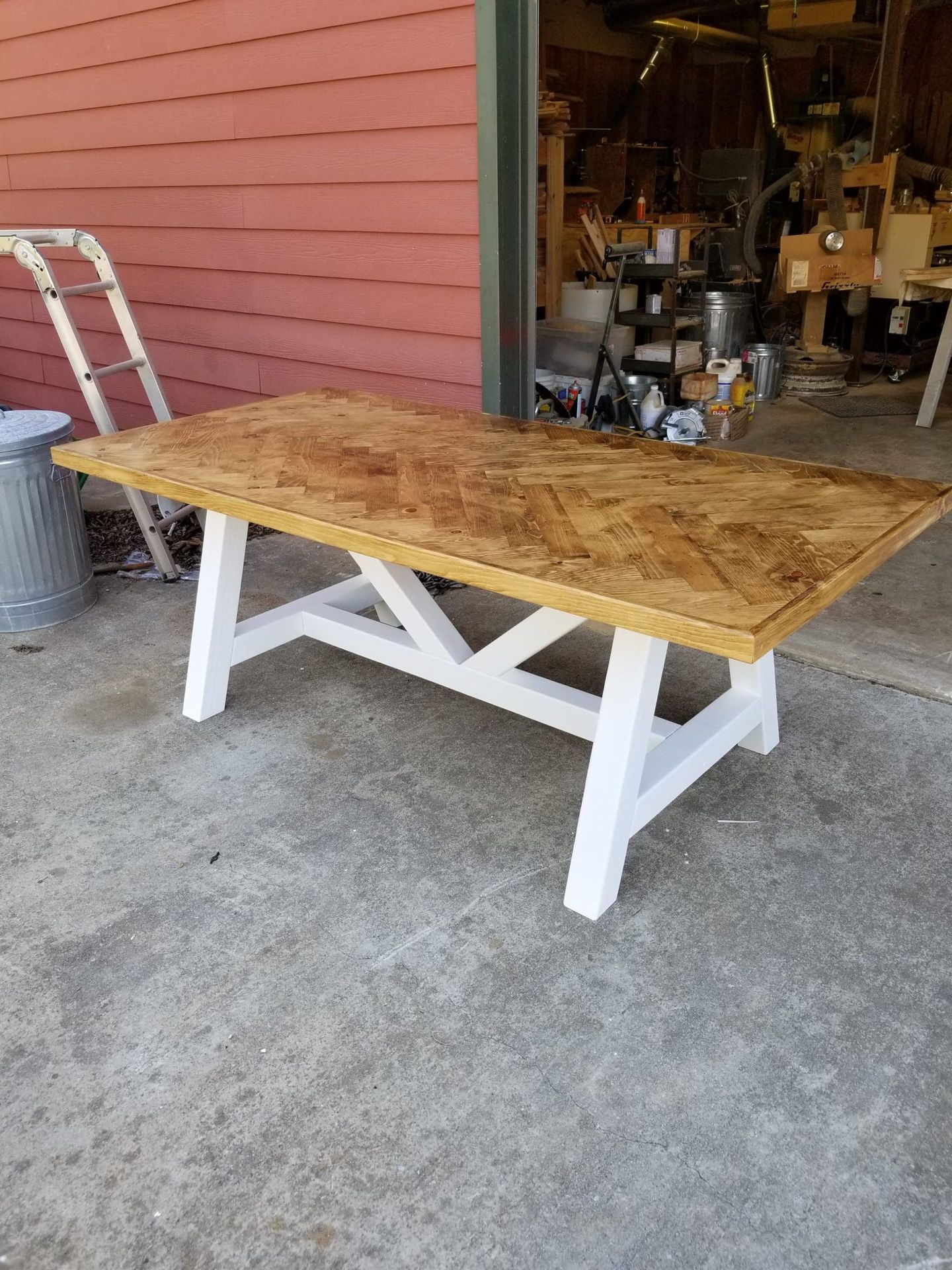 A wooden table with white legs is sitting in front of a garage door.