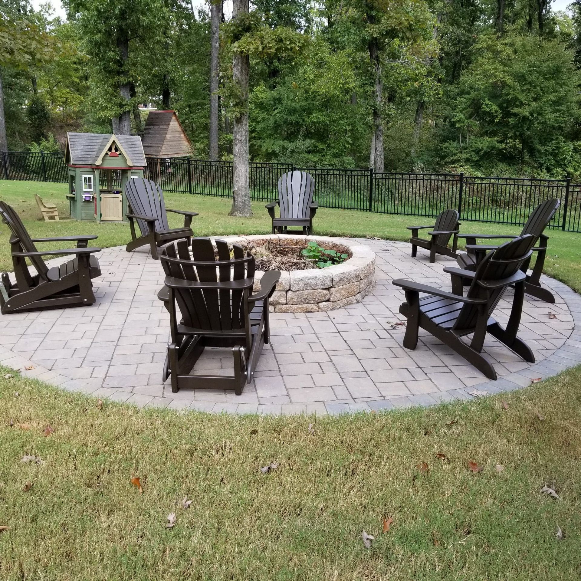 A fire pit with chairs around it in a backyard.