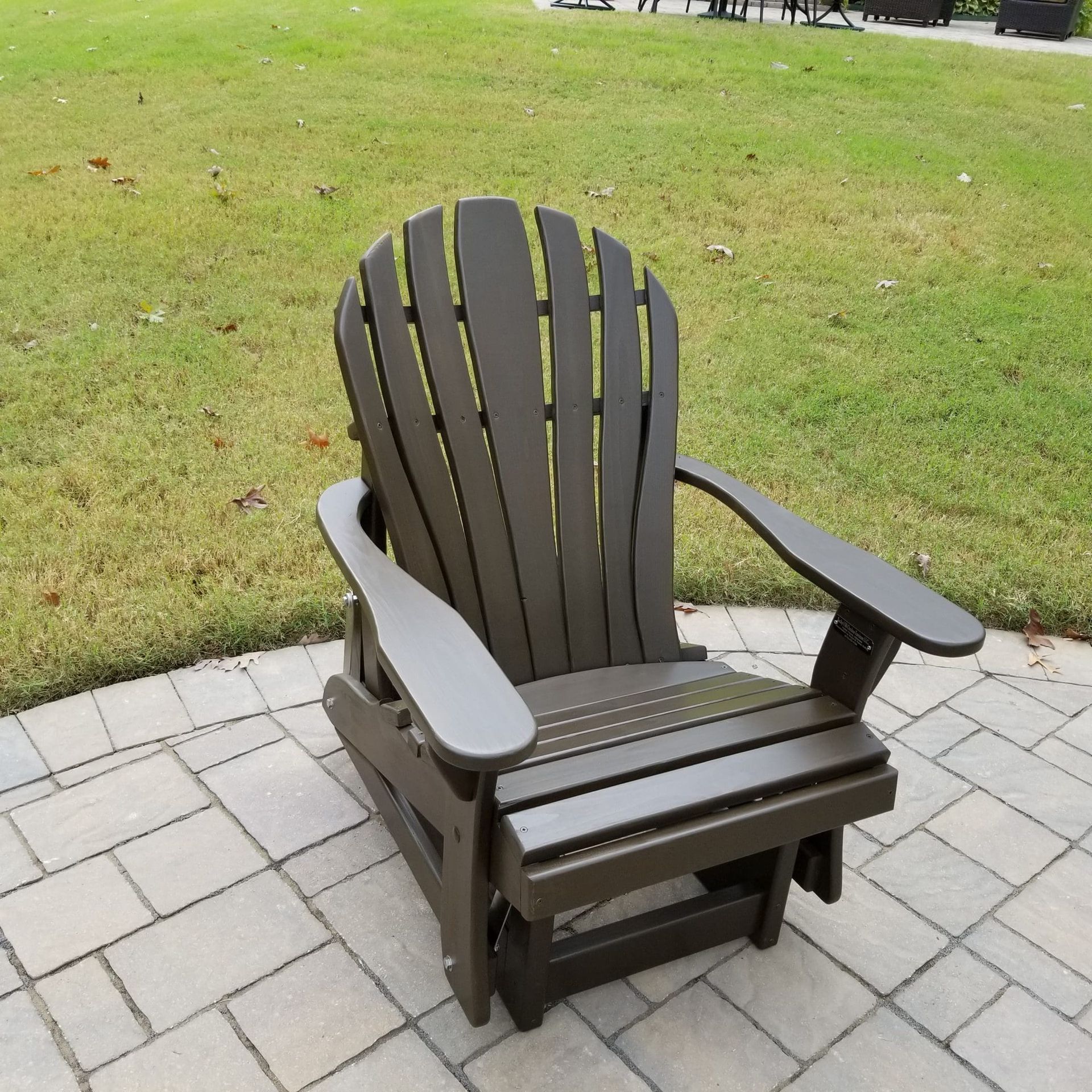 A brown adirondack chair is sitting on a brick patio