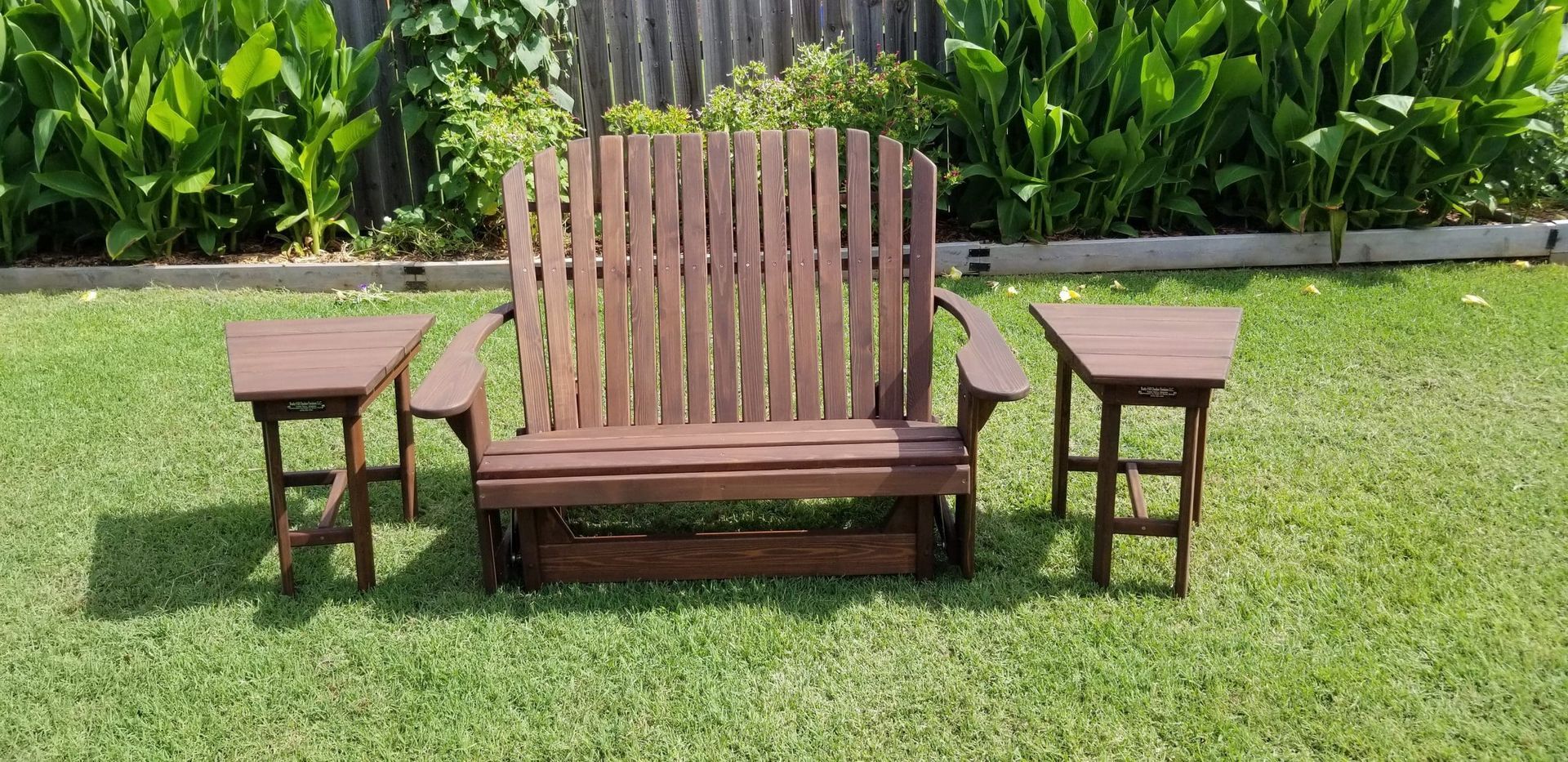 A wooden bench and two tables are sitting on top of a lush green lawn.