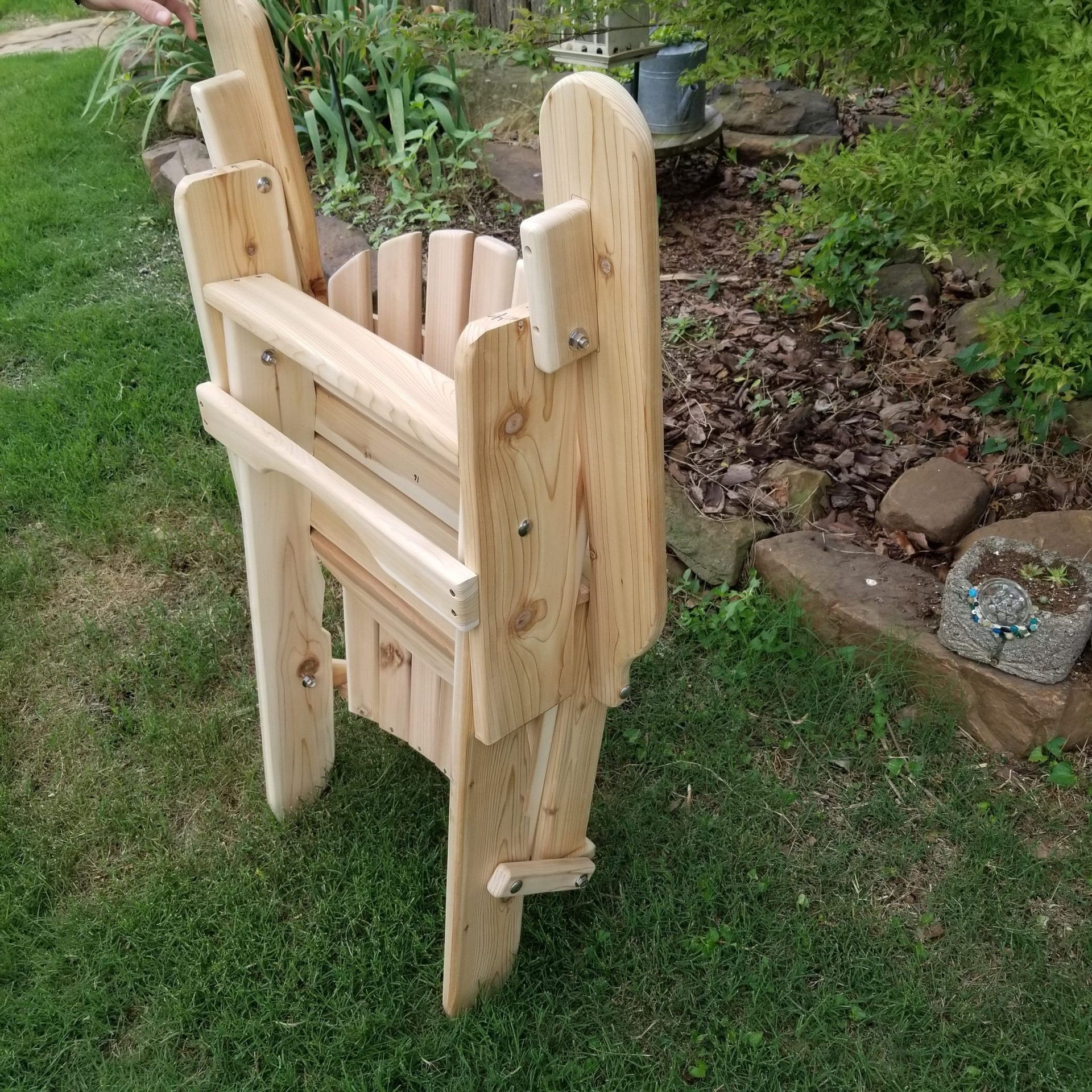 A wooden chair is sitting in the grass in a garden