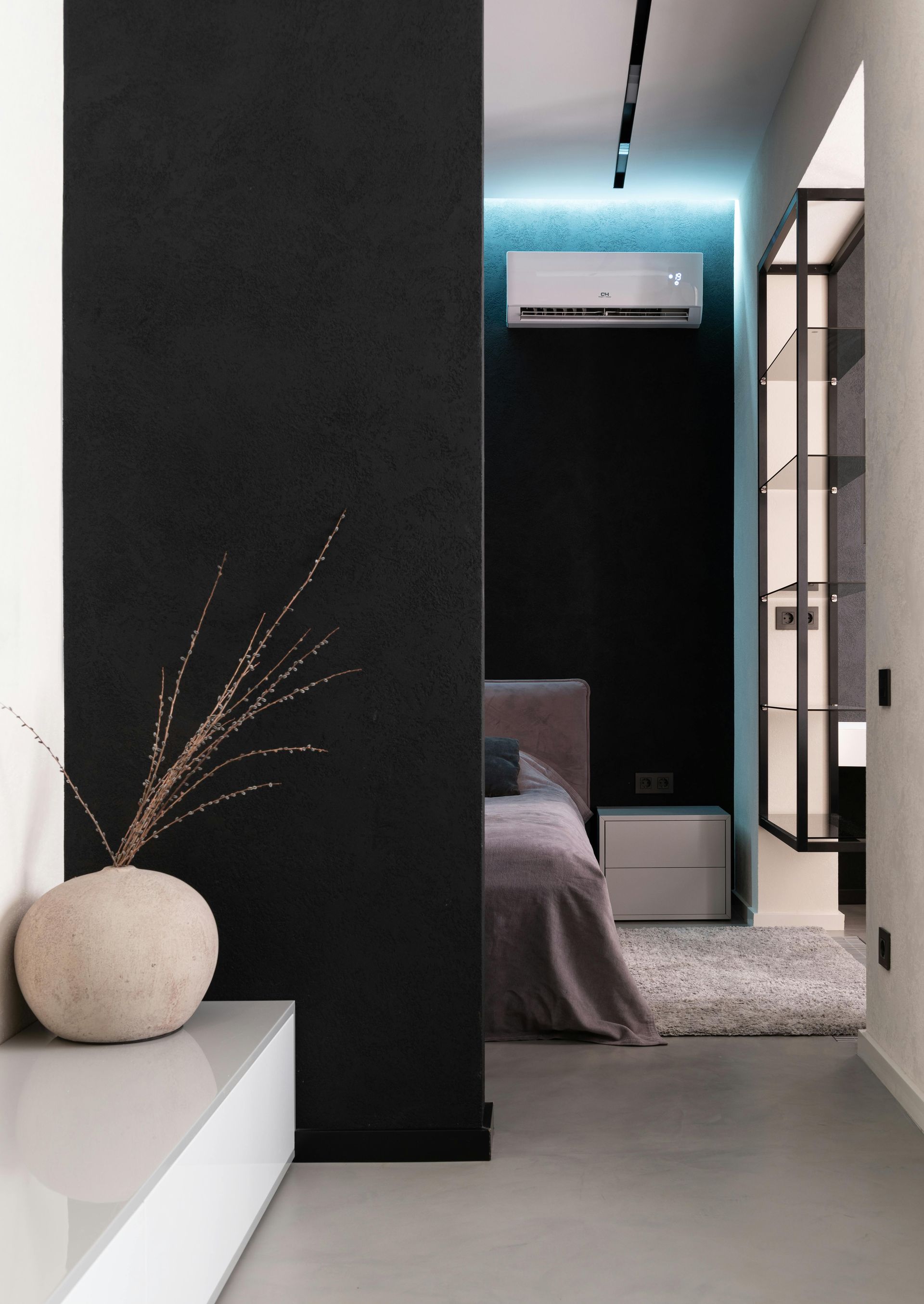 Modern bedroom interior with black accent wall, bed, and decorative vase.