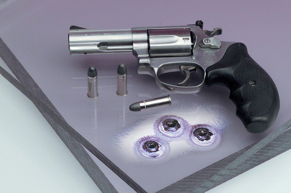 A stainless steel revolver with bullets on a purple background