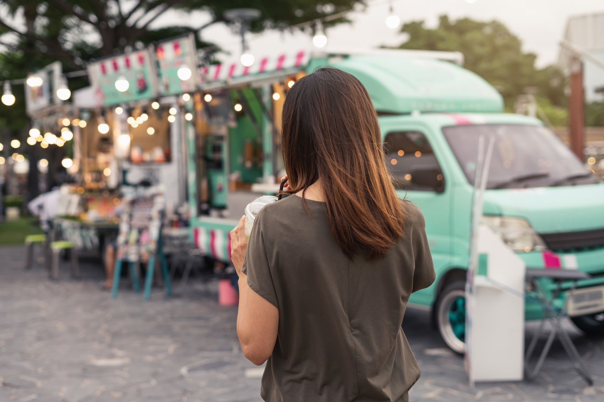 A woman is standing in front of a green food truck.