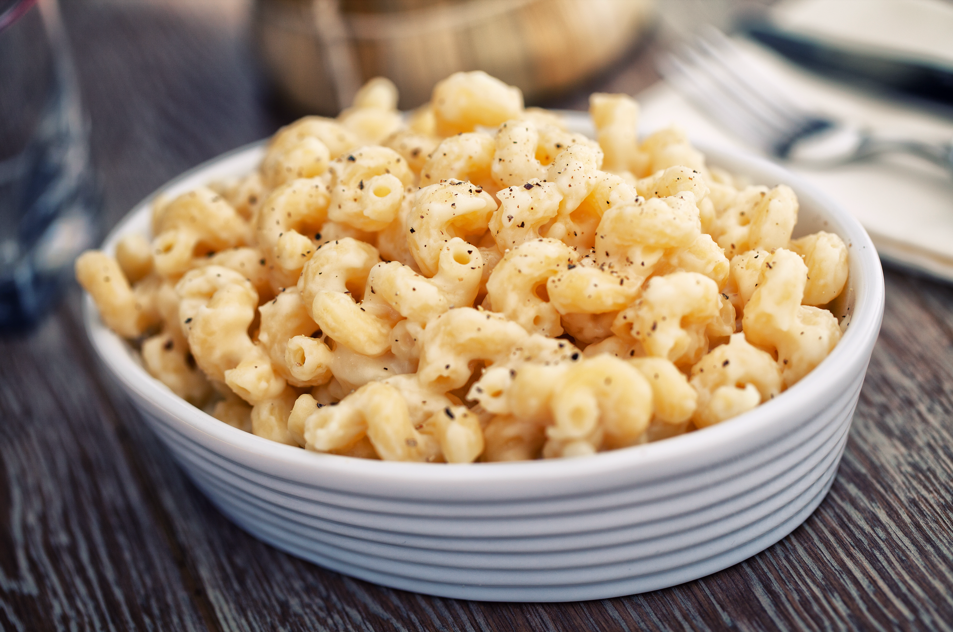 A bowl of macaroni and cheese is sitting on a wooden table.