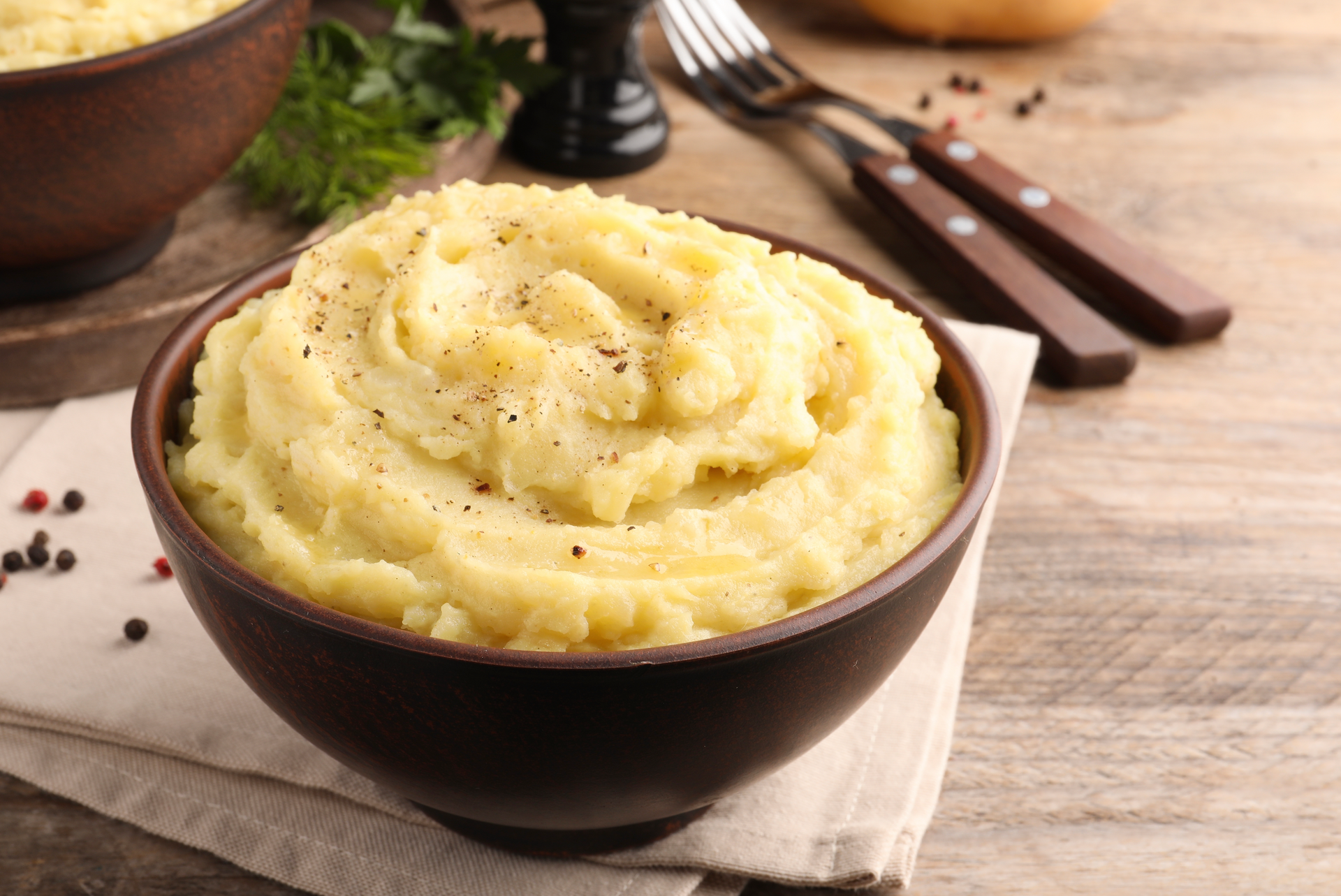 A bowl of mashed potatoes is sitting on a wooden table.
