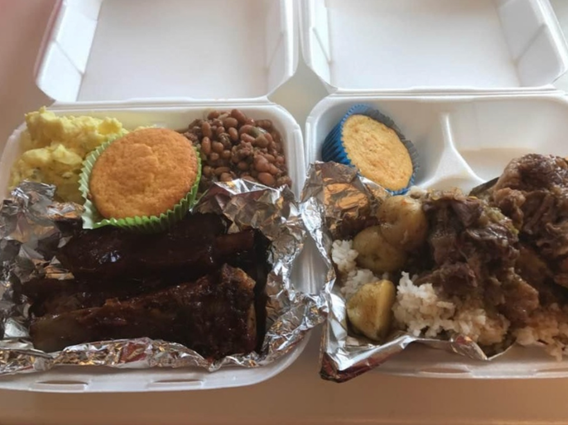 Two styrofoam containers filled with food are sitting on a table.