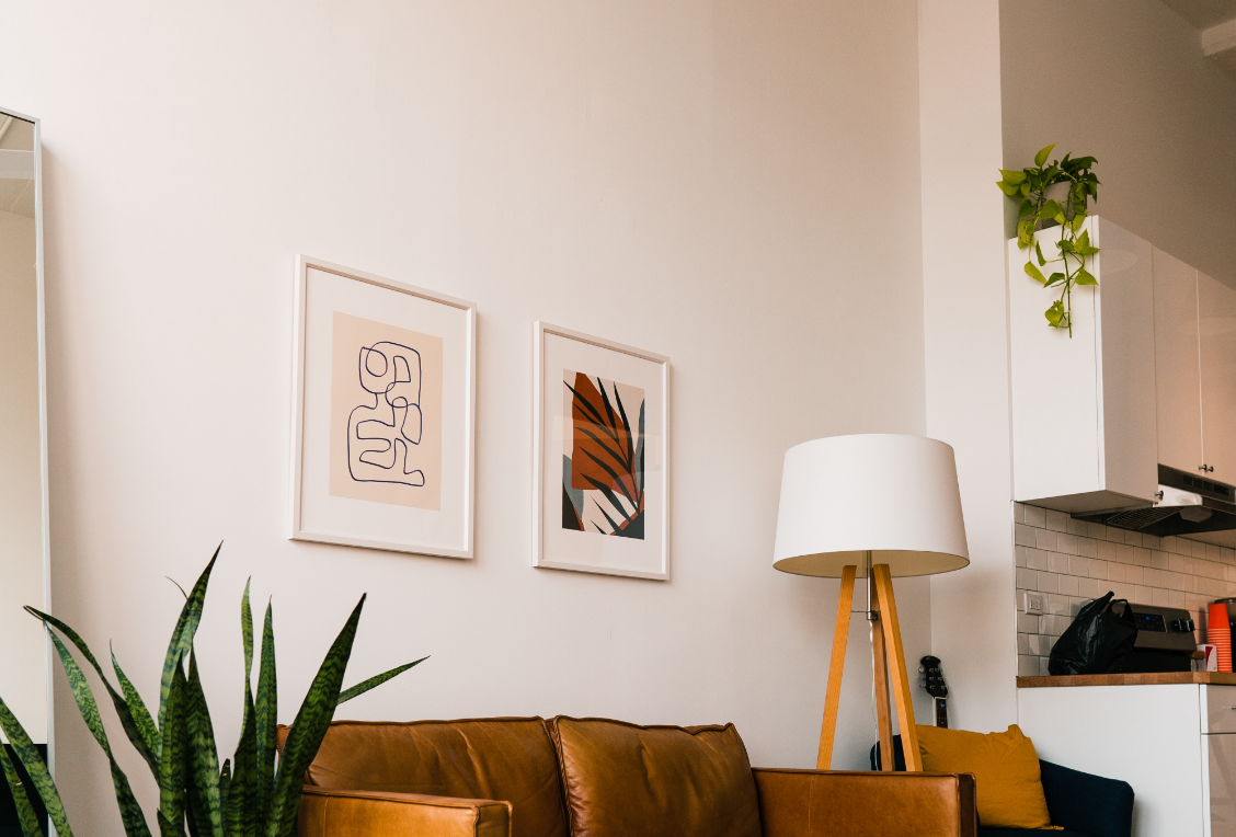 A living room with a couch , chair , lamp and plants.
