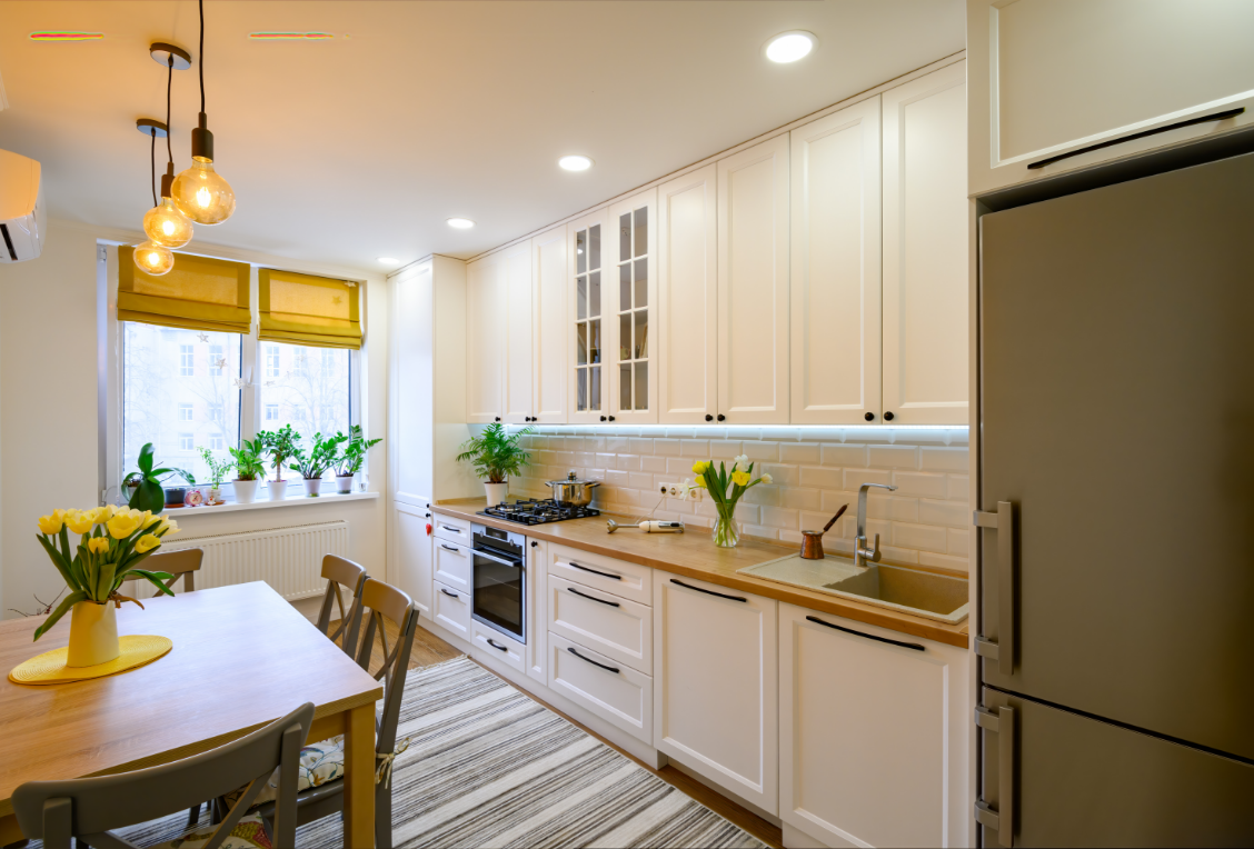 A kitchen with white cabinets , wooden counter tops , a table and chairs.