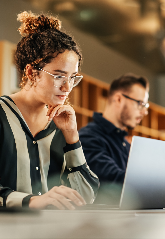 A woman is sitting at a table using a laptop computer.