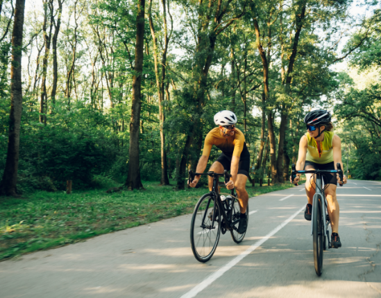 A man and a woman are riding bicycles down a road.