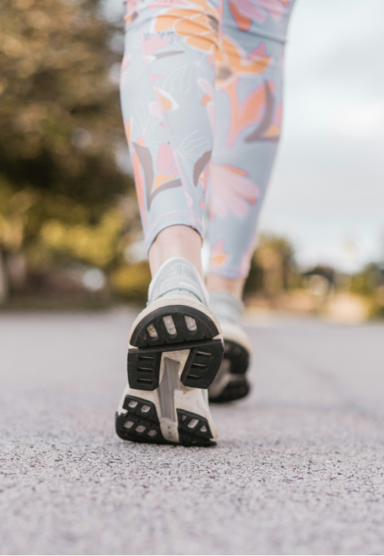 A close up of a person 's feet walking down a road.