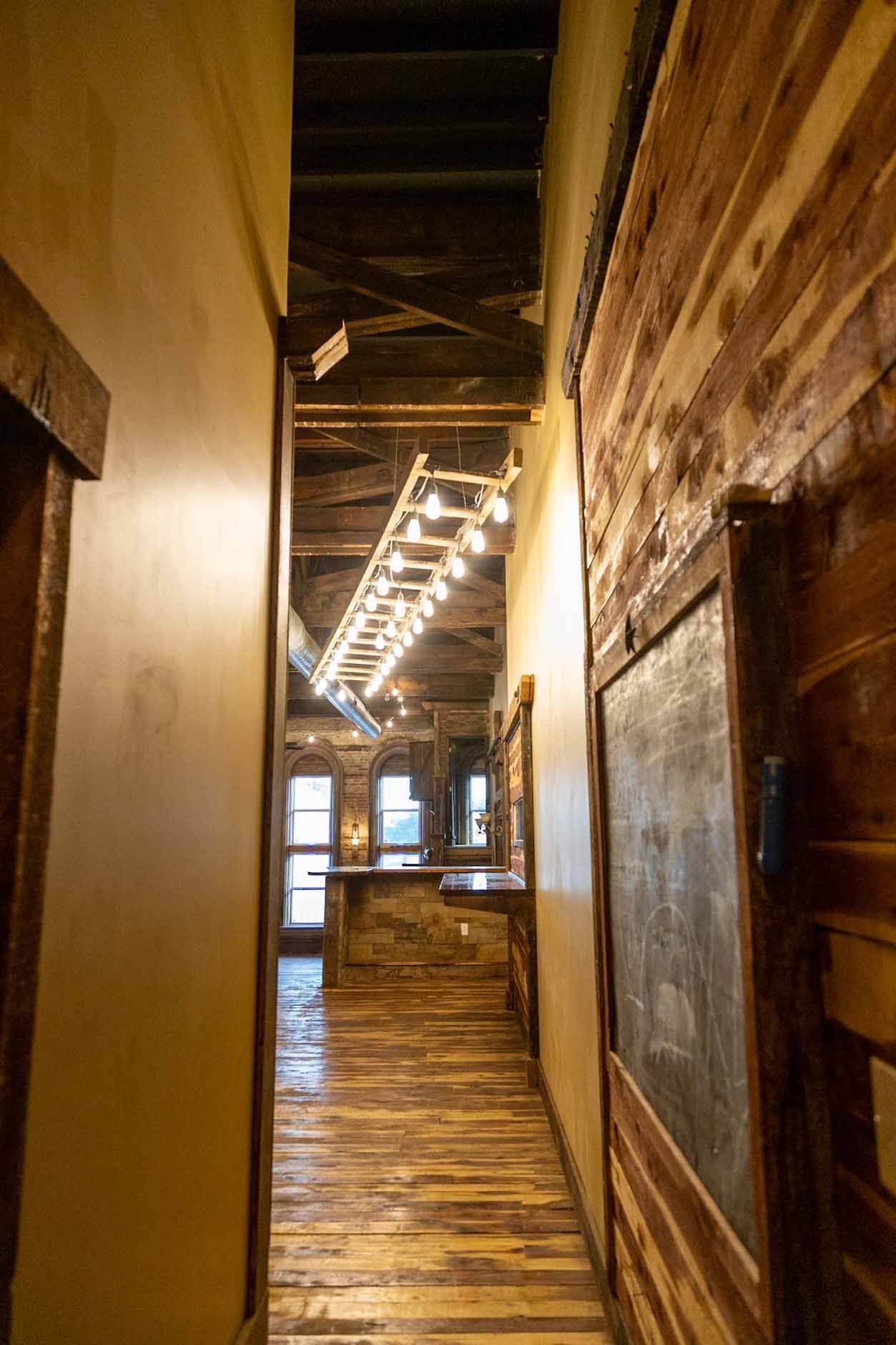 A long hallway with wooden floors and a chalkboard on the wall.