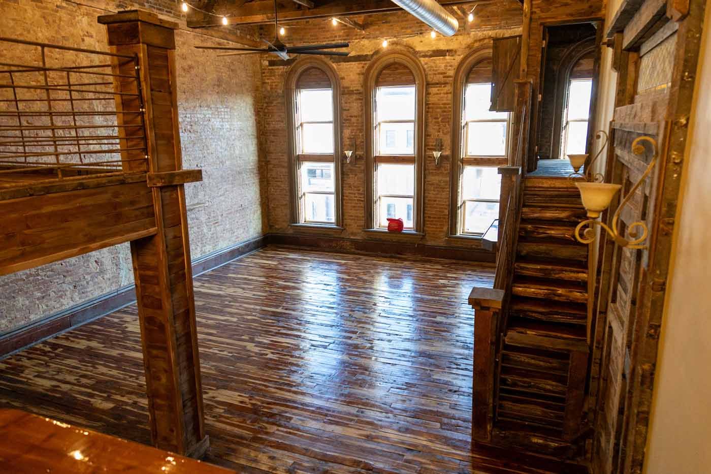 An empty room with a wooden floor and stairs leading up to the second floor.