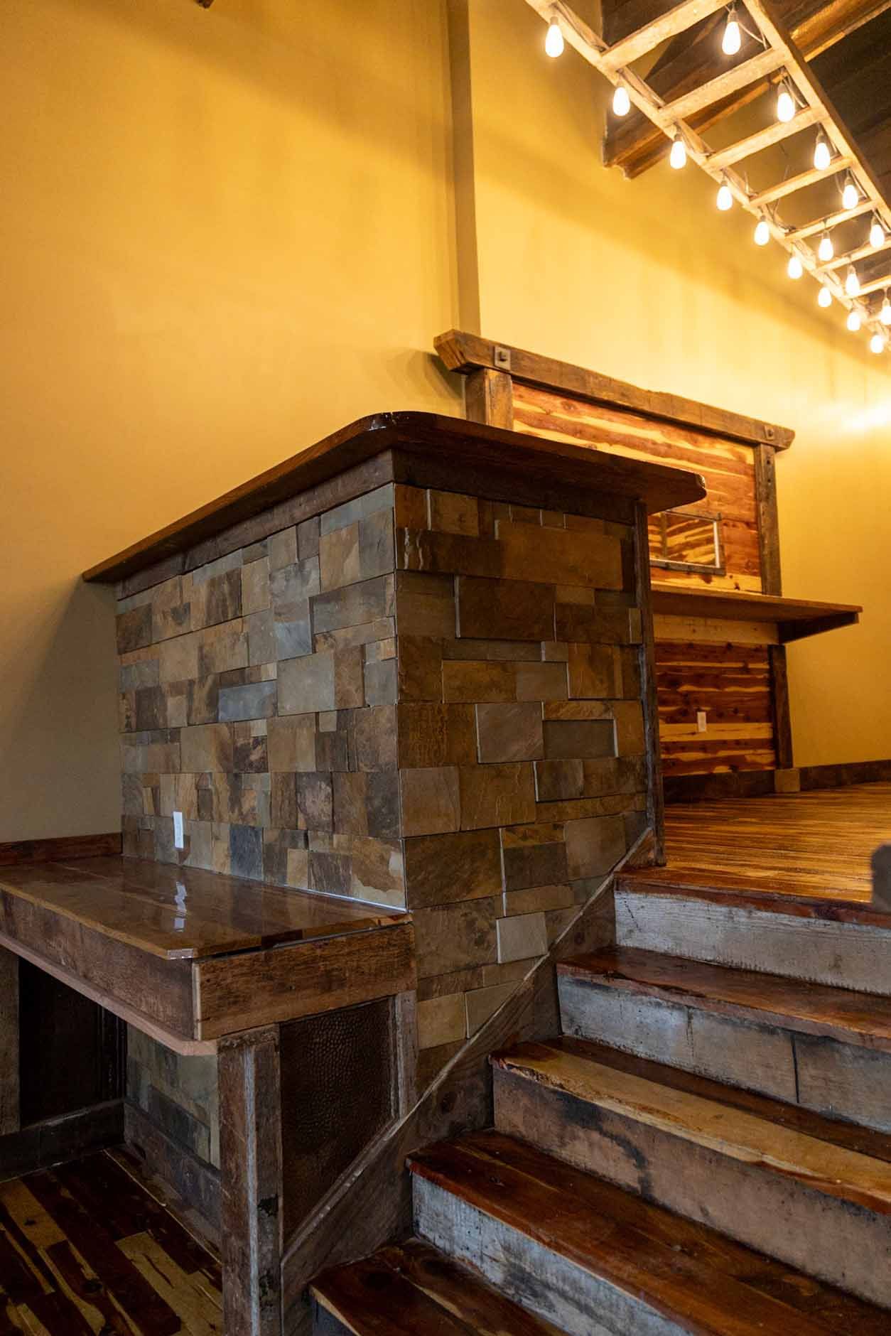 A staircase with a stone wall and wooden steps in a room.