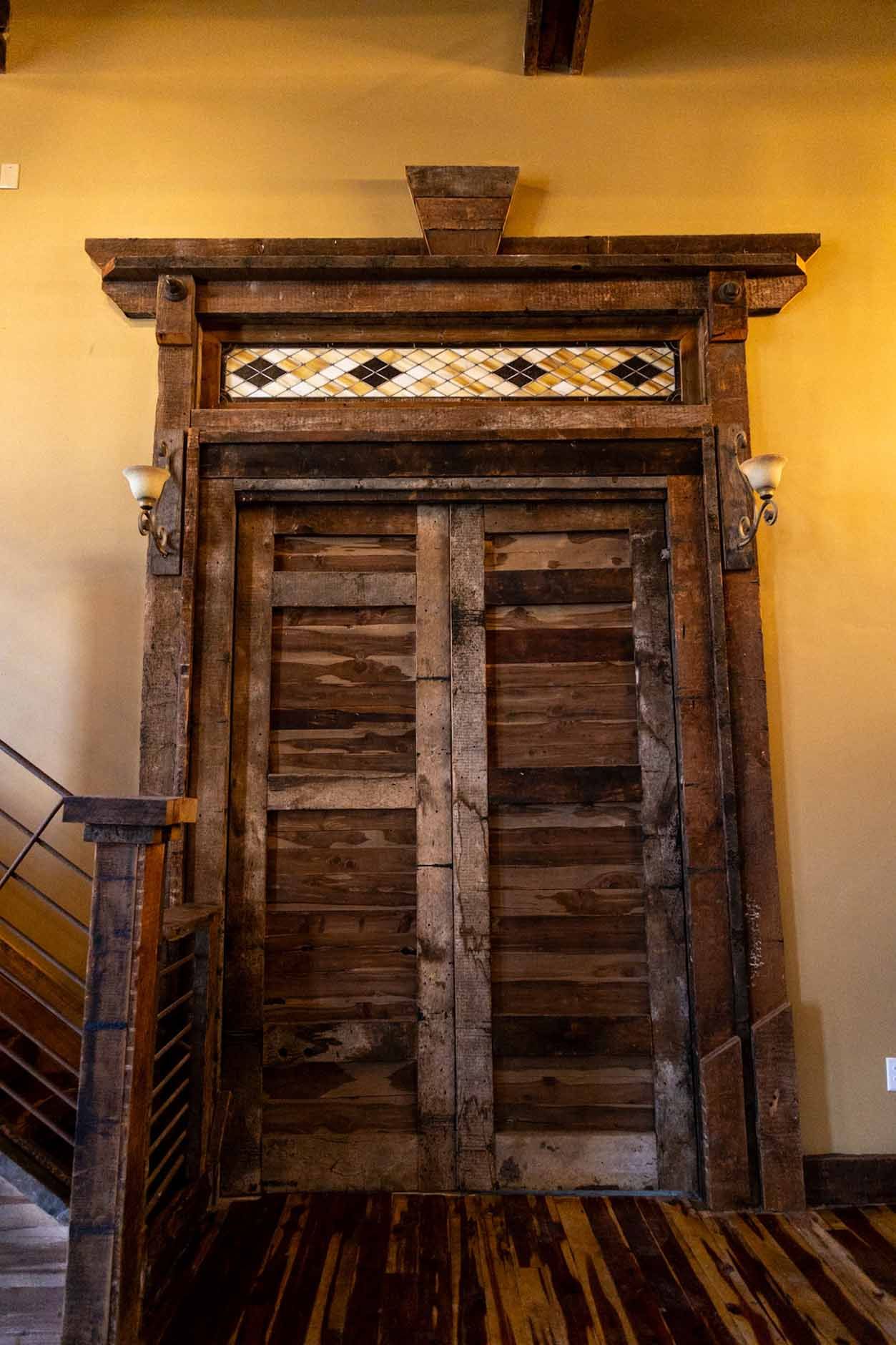 A wooden door with a staircase in the background.
