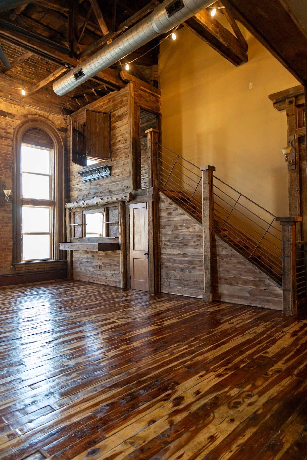 An empty room with a wooden floor and stairs.