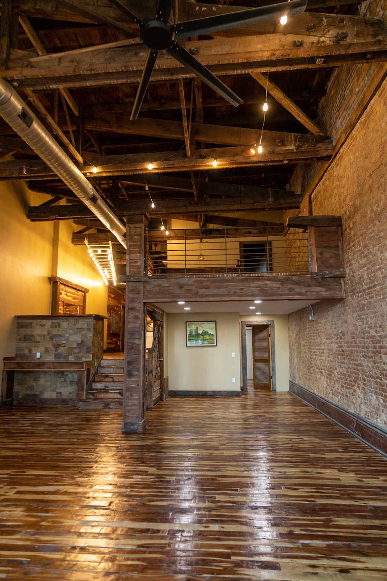 A large empty room with wooden floors and a ceiling fan.
