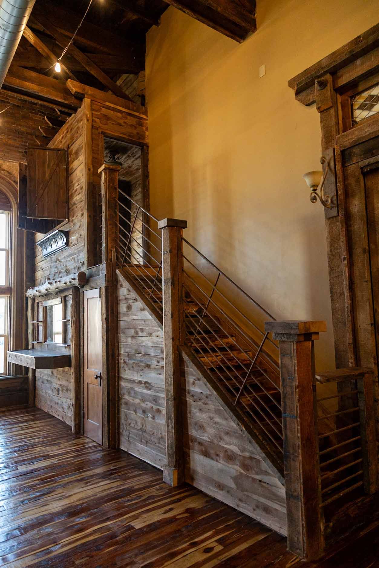 A wooden staircase with a metal railing in a room with a wooden floor.