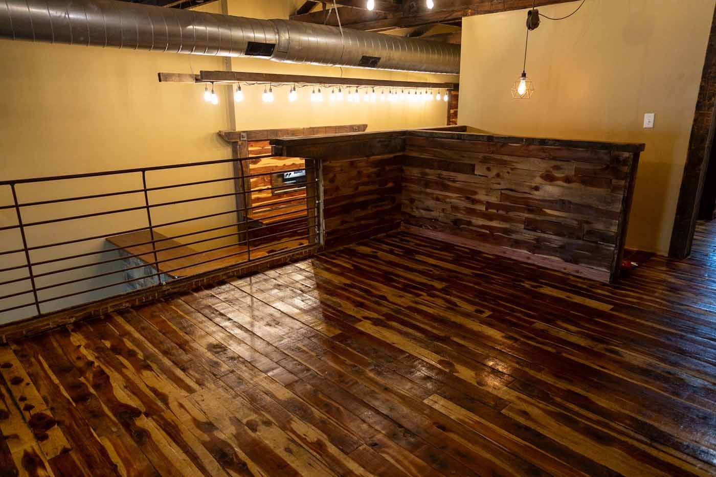 An empty room with a wooden floor and a metal railing.