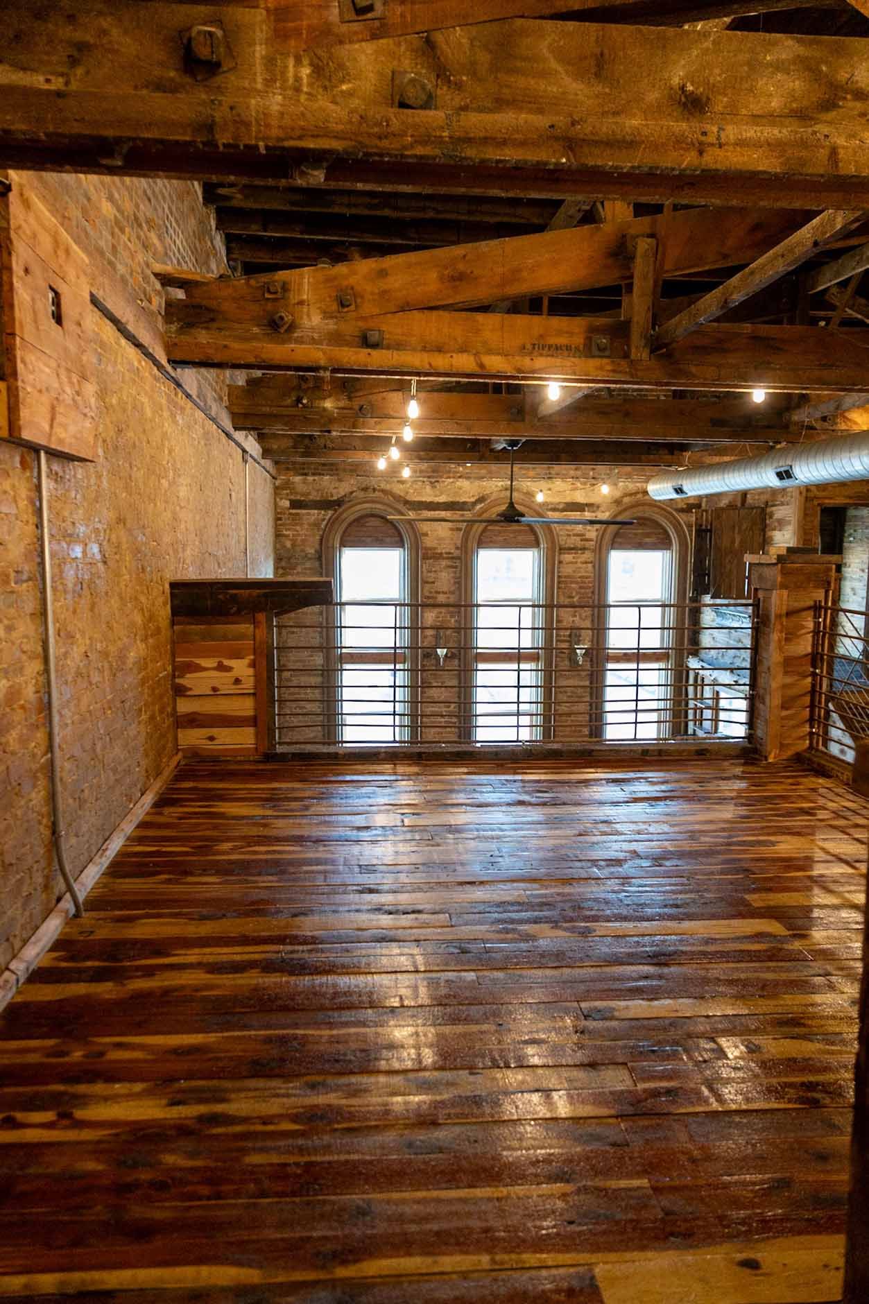 An empty room with wooden floors and a brick wall.