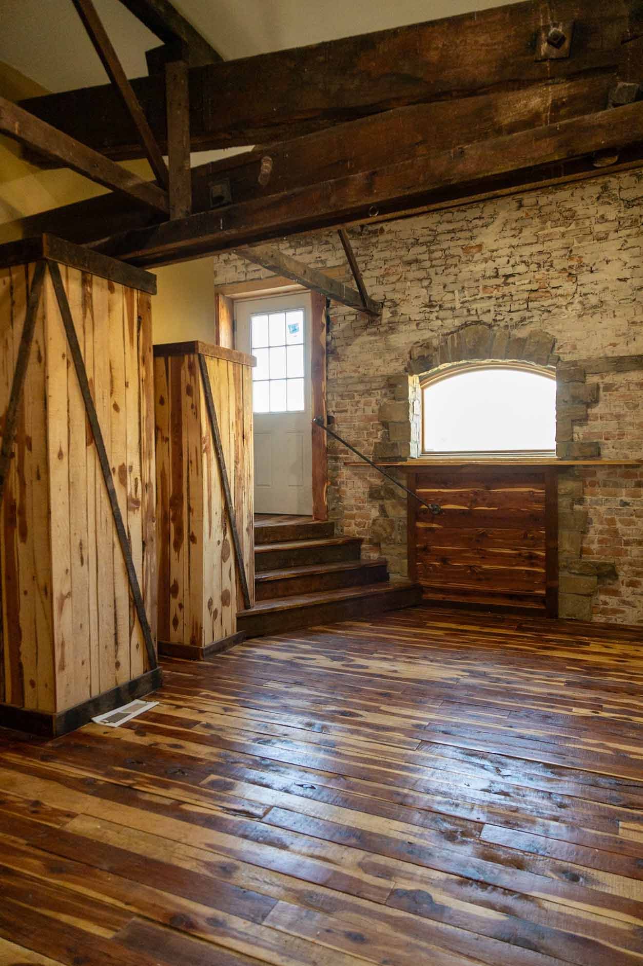 An empty room with wooden floors and a brick wall.