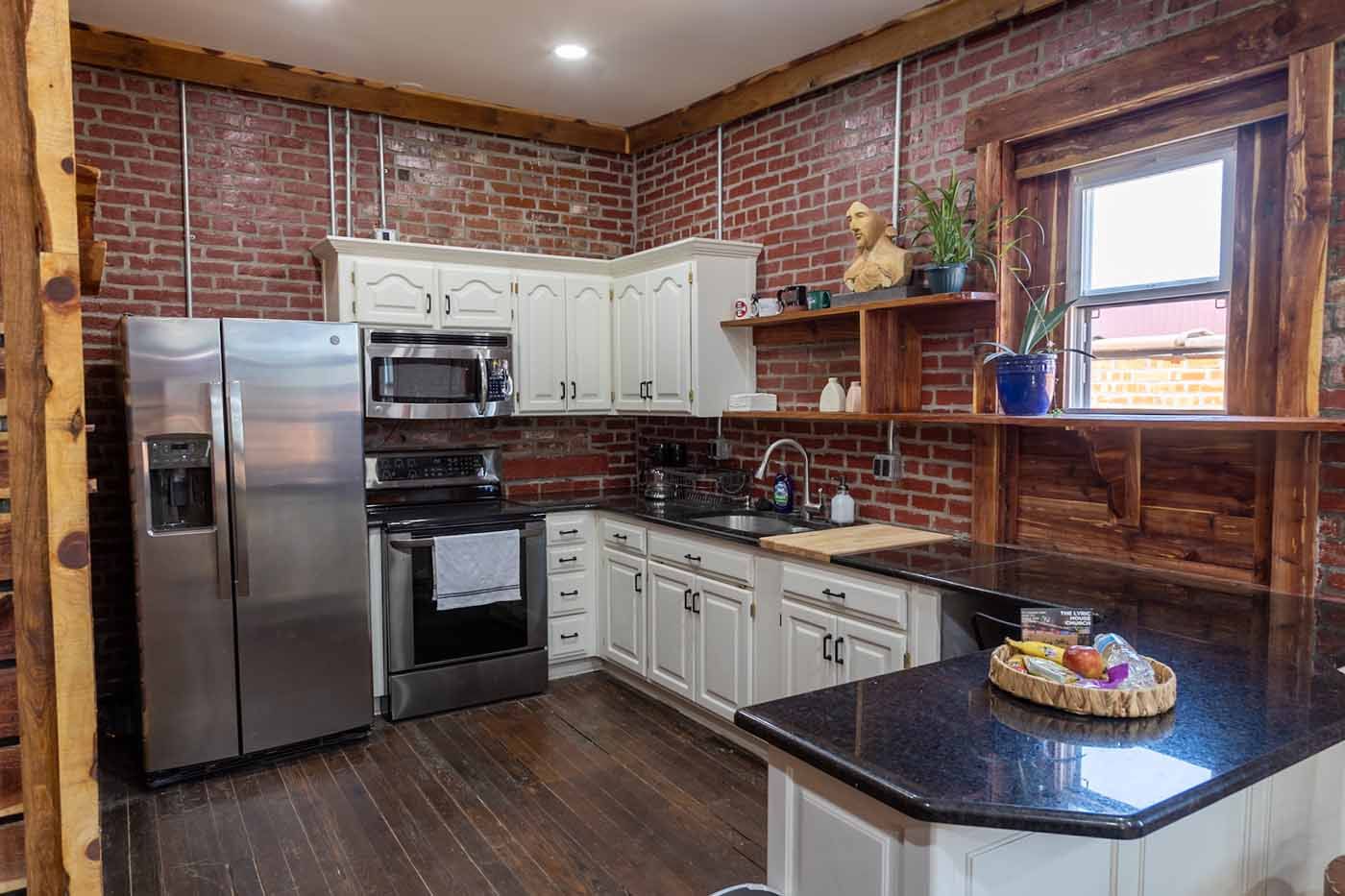 A kitchen with stainless steel appliances and a brick wall.