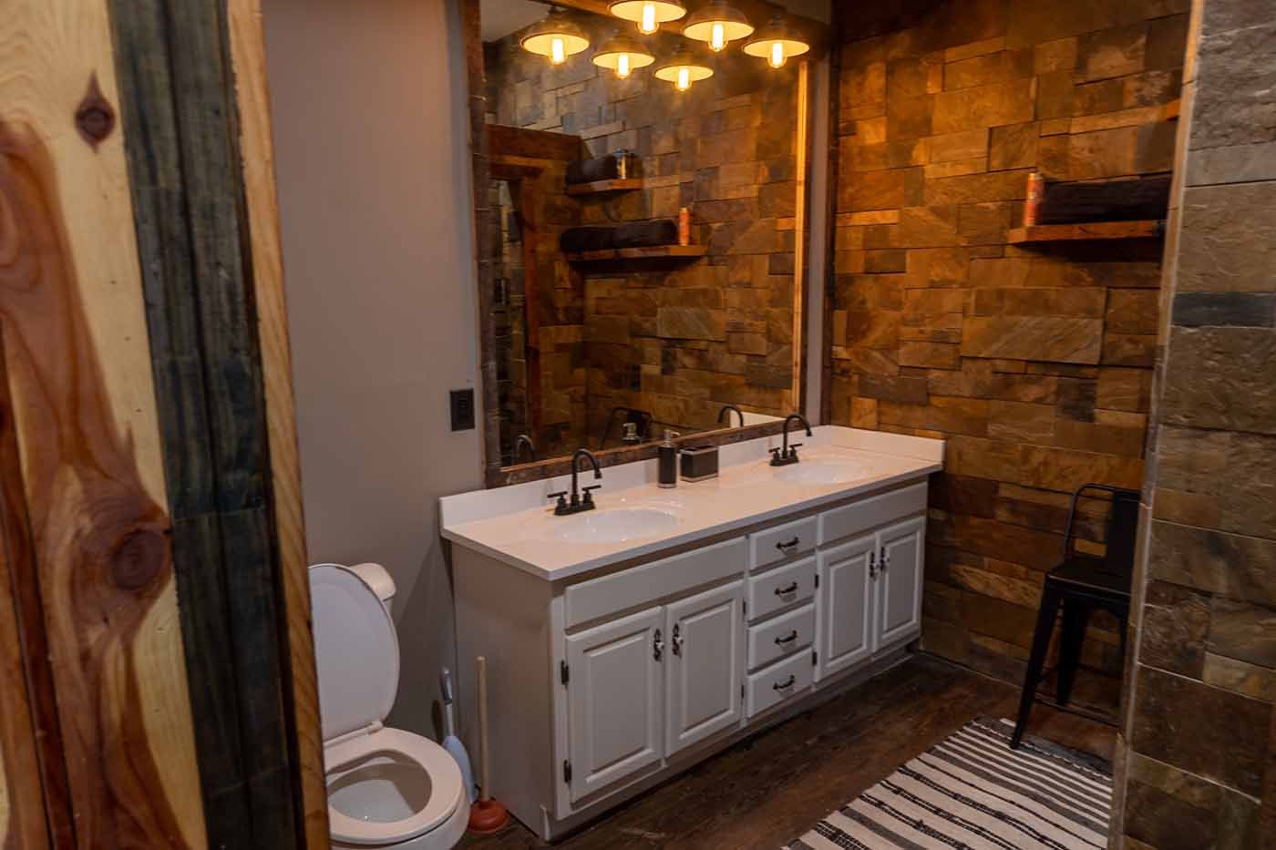 A bathroom with two sinks , a toilet , and a large mirror.
