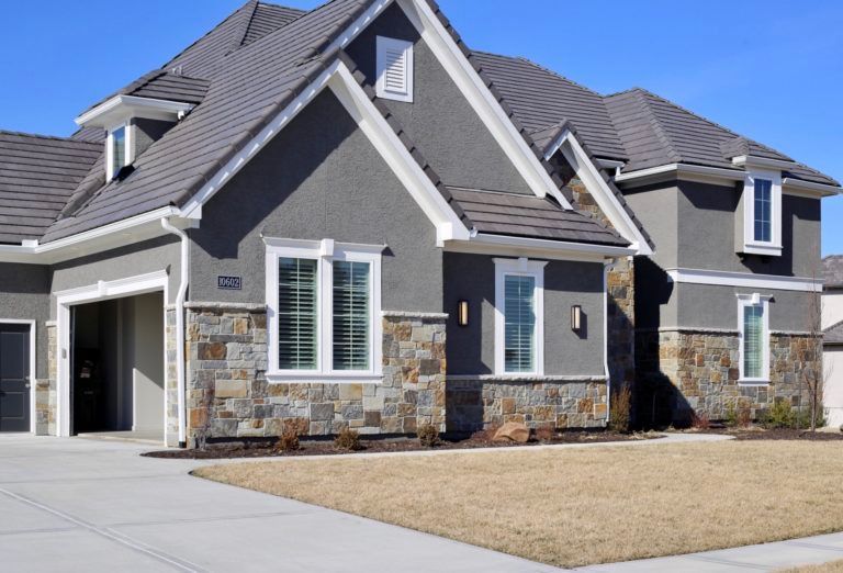A large house with a stone facade and a gray roof