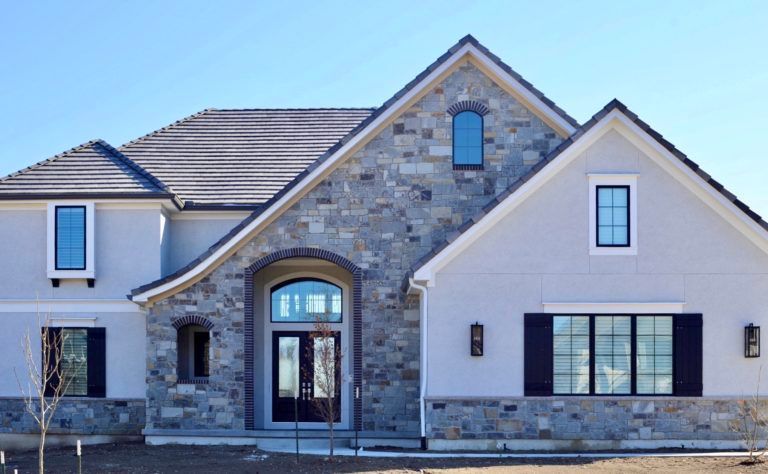 A large house with a stone facade and black shutters