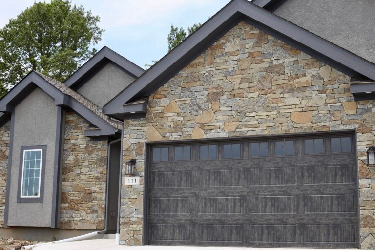A house with a stone facade and a black garage door