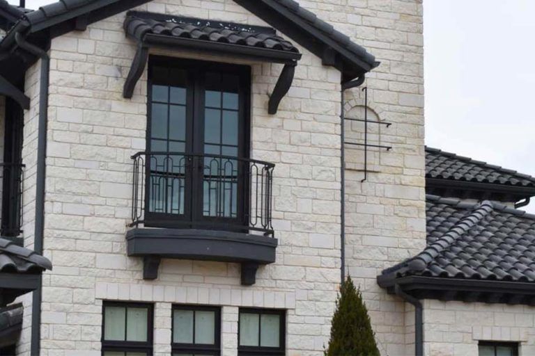 A white brick building with black windows and a balcony