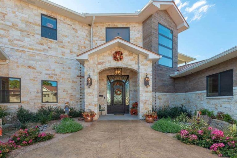 A large brick house with a black door and a wreath on the front door.
