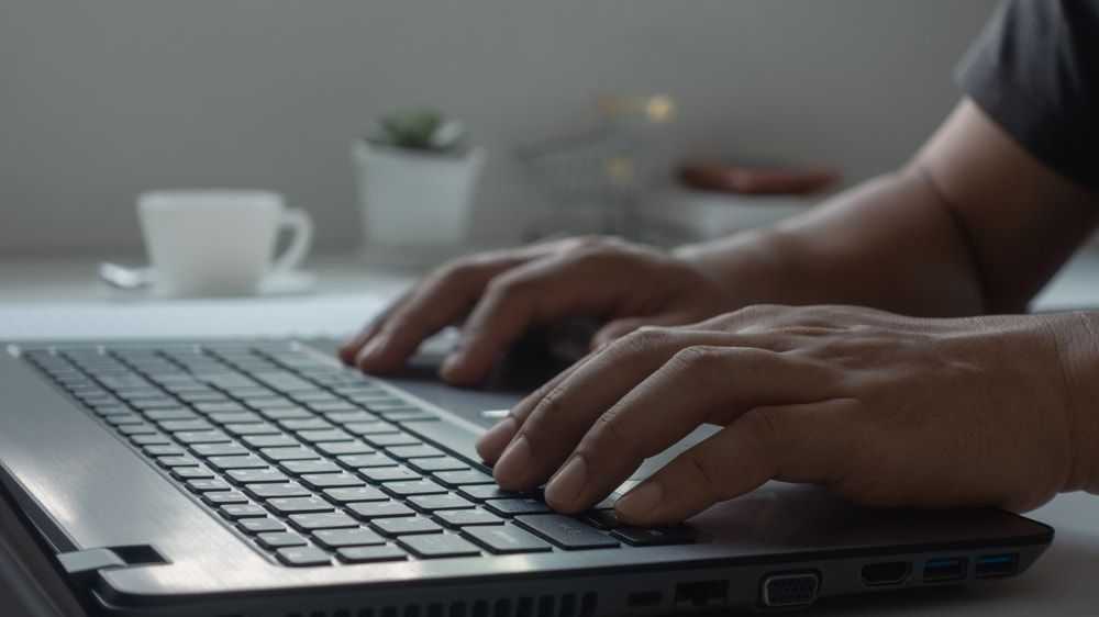 a Person is Typing on a Laptop Computer — Adaptive PC Solutions In Manoora, QLD