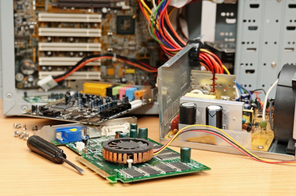 A Computer Motherboard Is Sitting On A Wooden Table Next To A Screwdriver — Adaptive PC Solutions in Manoora, QLD