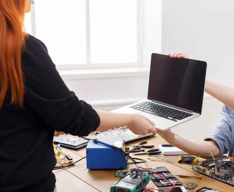 A Man And A Woman Are Working On A Laptop Computer — Adaptive PC Solutions in Manoora, QLD