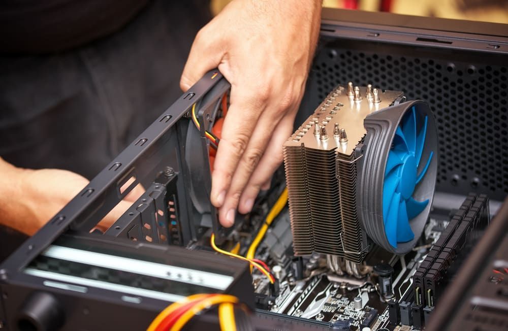 a Man is Fixing a Computer With a Fan — Adaptive PC Solutions in Manoora, QLD