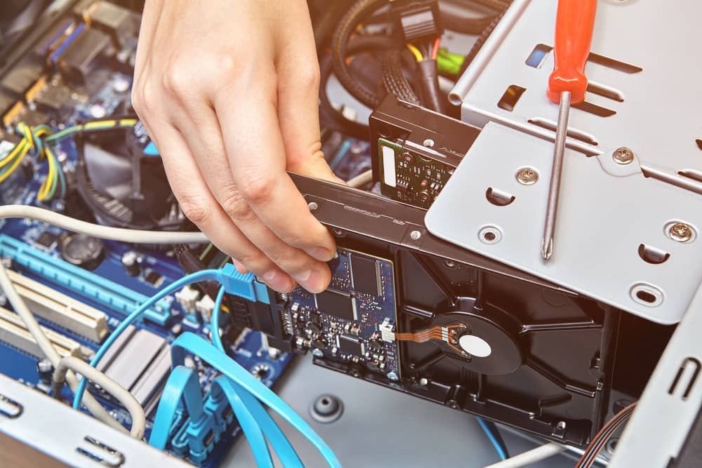 a Person is Fixing a Computer With a Screwdriver — Adaptive PC Solutions In Manoora, QLD