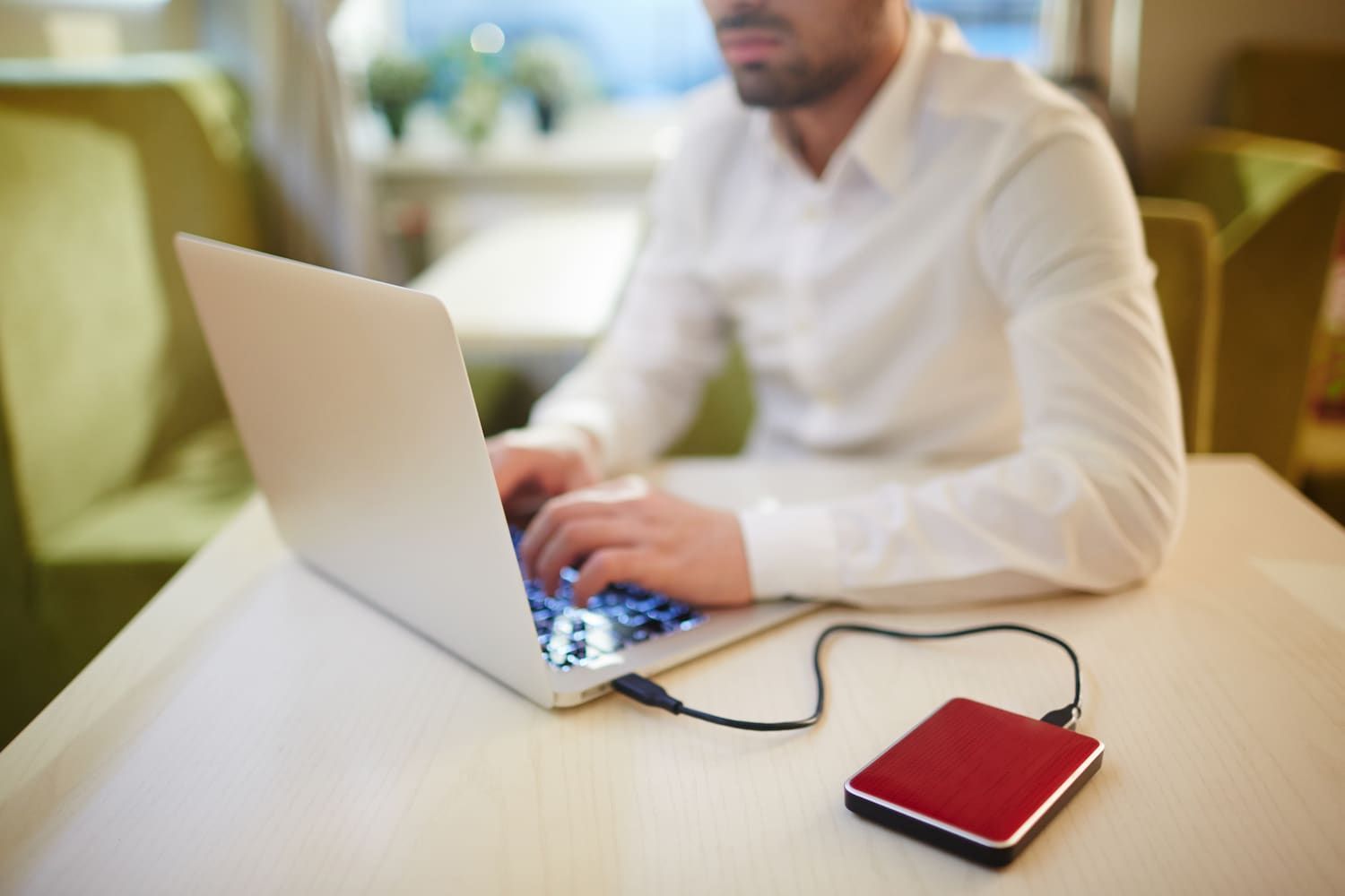 a Man is Sitting at a Table Using a Laptop Computer — Adaptive PC Solutions in Manoora, QLD