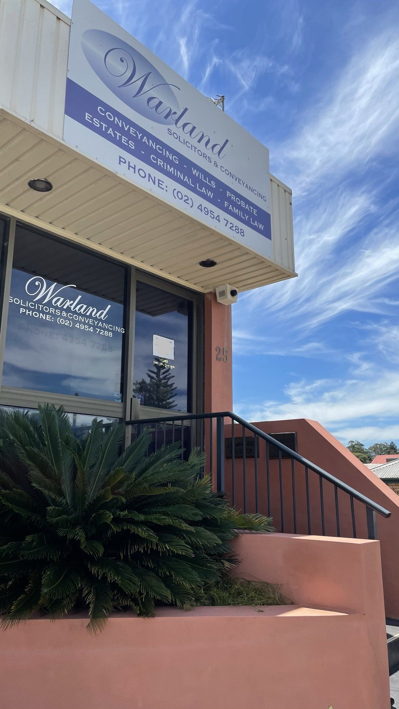 The Front of a Building With a Sign on It and Stairs Leading Up to It — Warland Solicitors in Cardiff, NSW