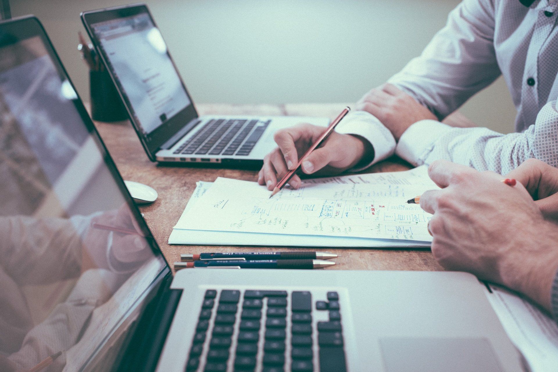 Two people reviewing paperwork beside open laptops during a conveyancing meeting.