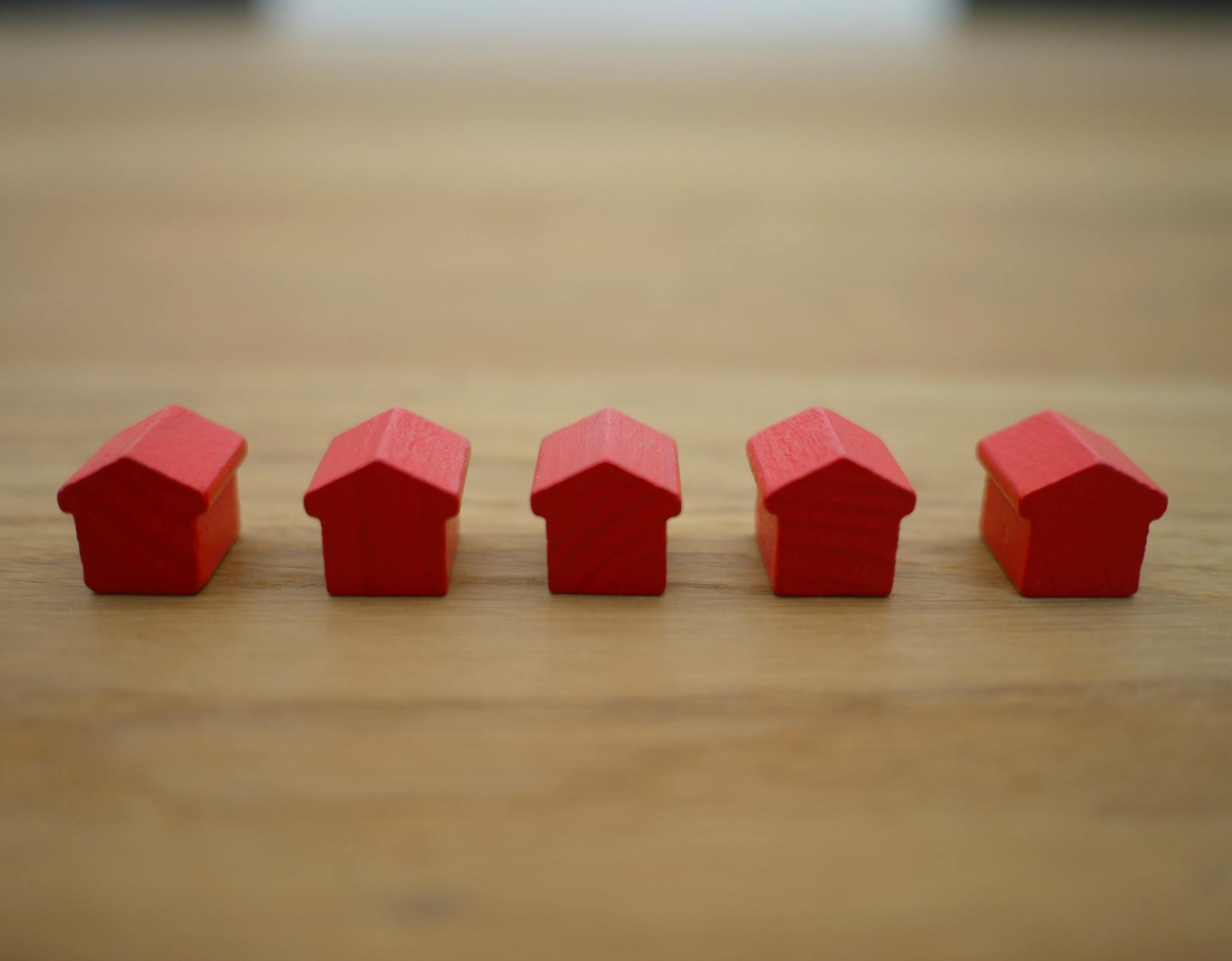 Five Red Houses Are Lined Up in a Row on a Wooden Table — Warland Solicitors in Cessnock, NSW